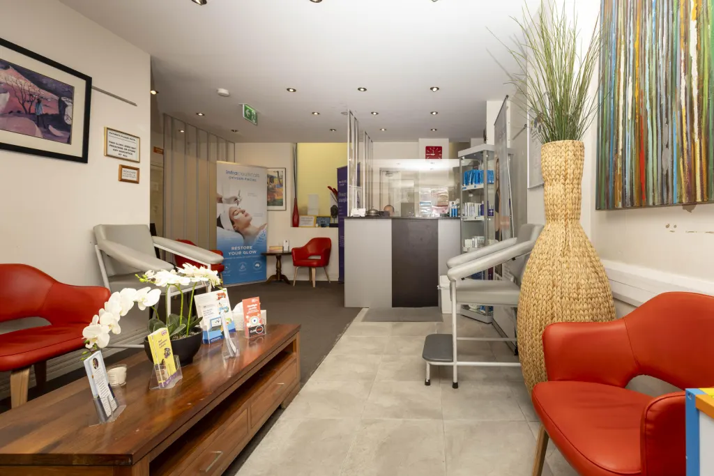 Clinicare waiting area with red armchairs, a timber coffee table and the reception desk beyond